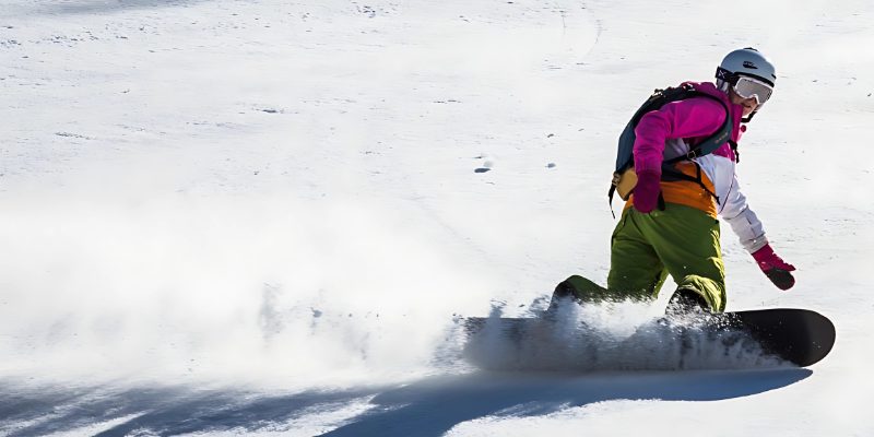 Snowboarder in kleurrijke outfit maakt afdalingen tijdens wintersport in Oostenrijk
