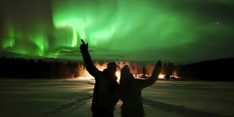 Jongeren kijken naar groen noorderlicht in Zweeds Lapland